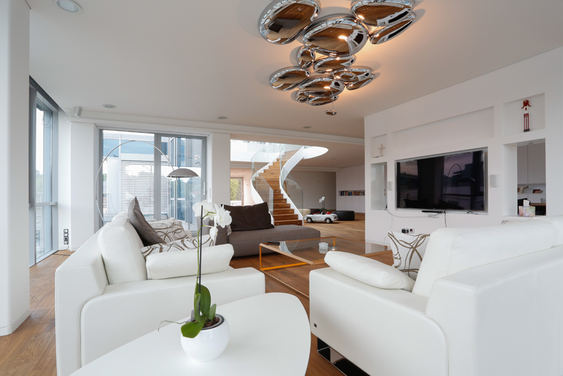 weißes Wohnzimmer mit großem Fernseher und gemütlichem Sofa von roomanddesign - Planungsbüro für Inneneinrichtungen